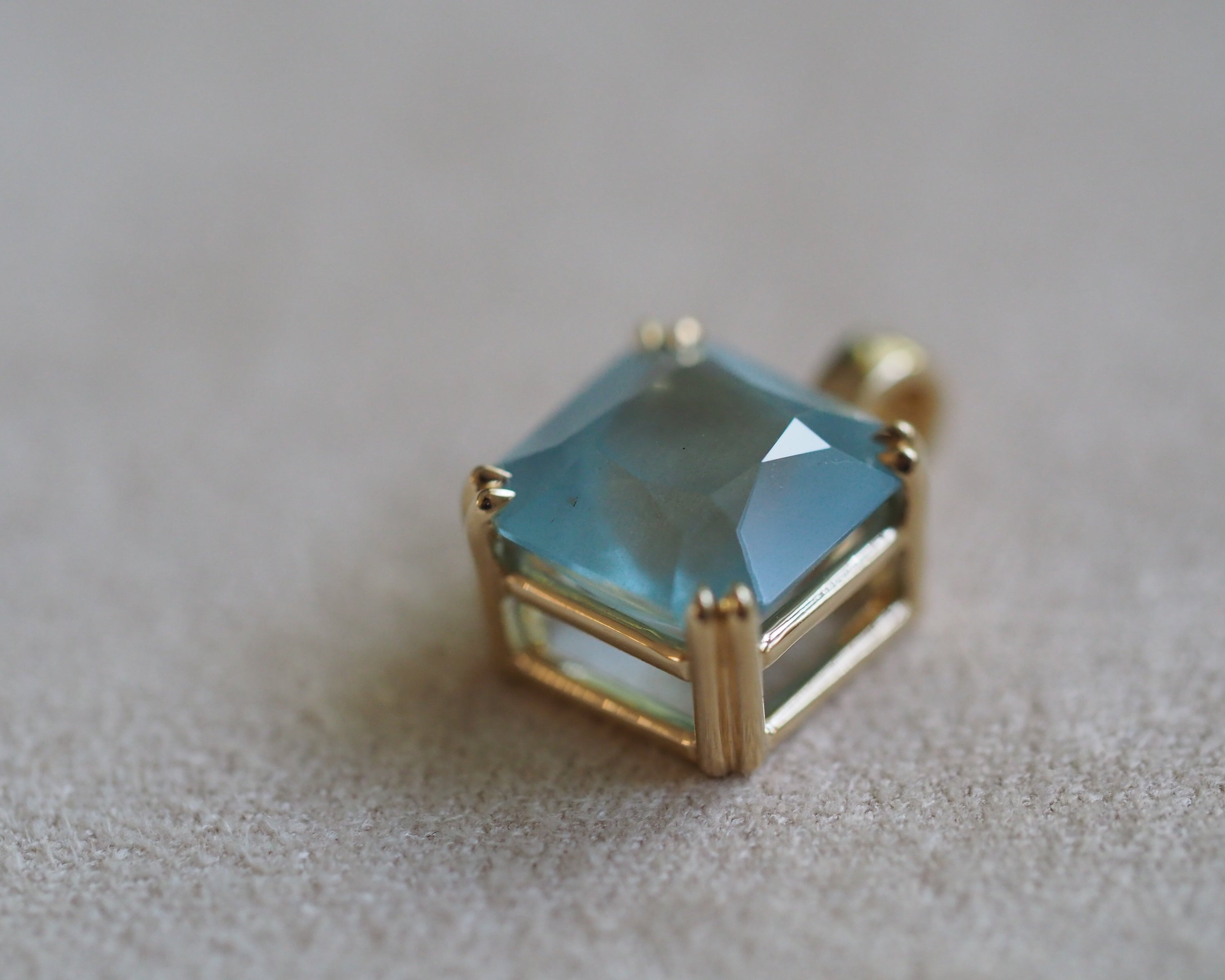 Carolyn Asscher Aquamarine pendant in front of a beige background