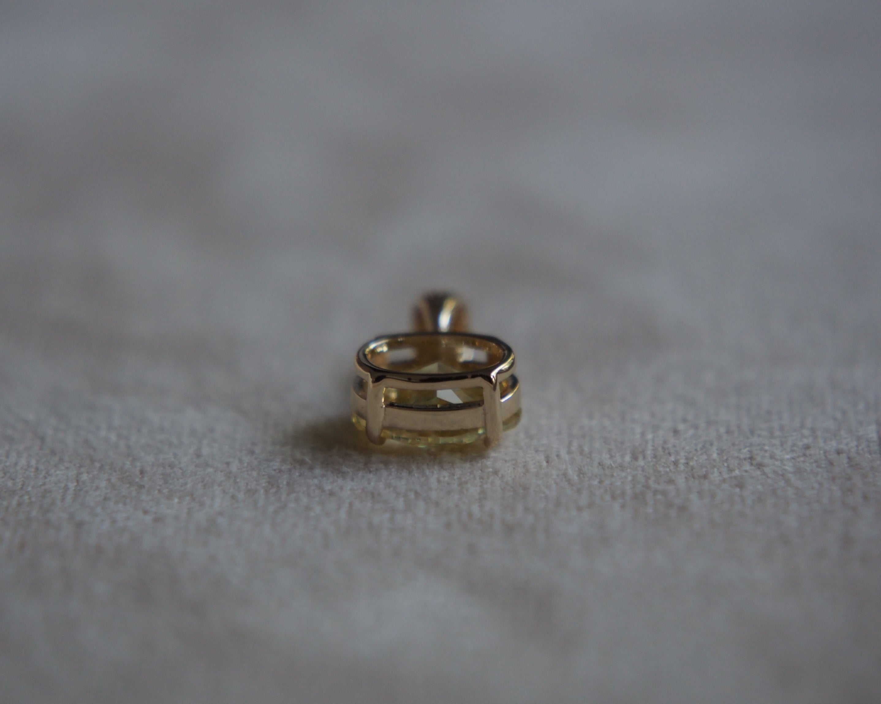 Bottom side of a gold pendant on a beige background