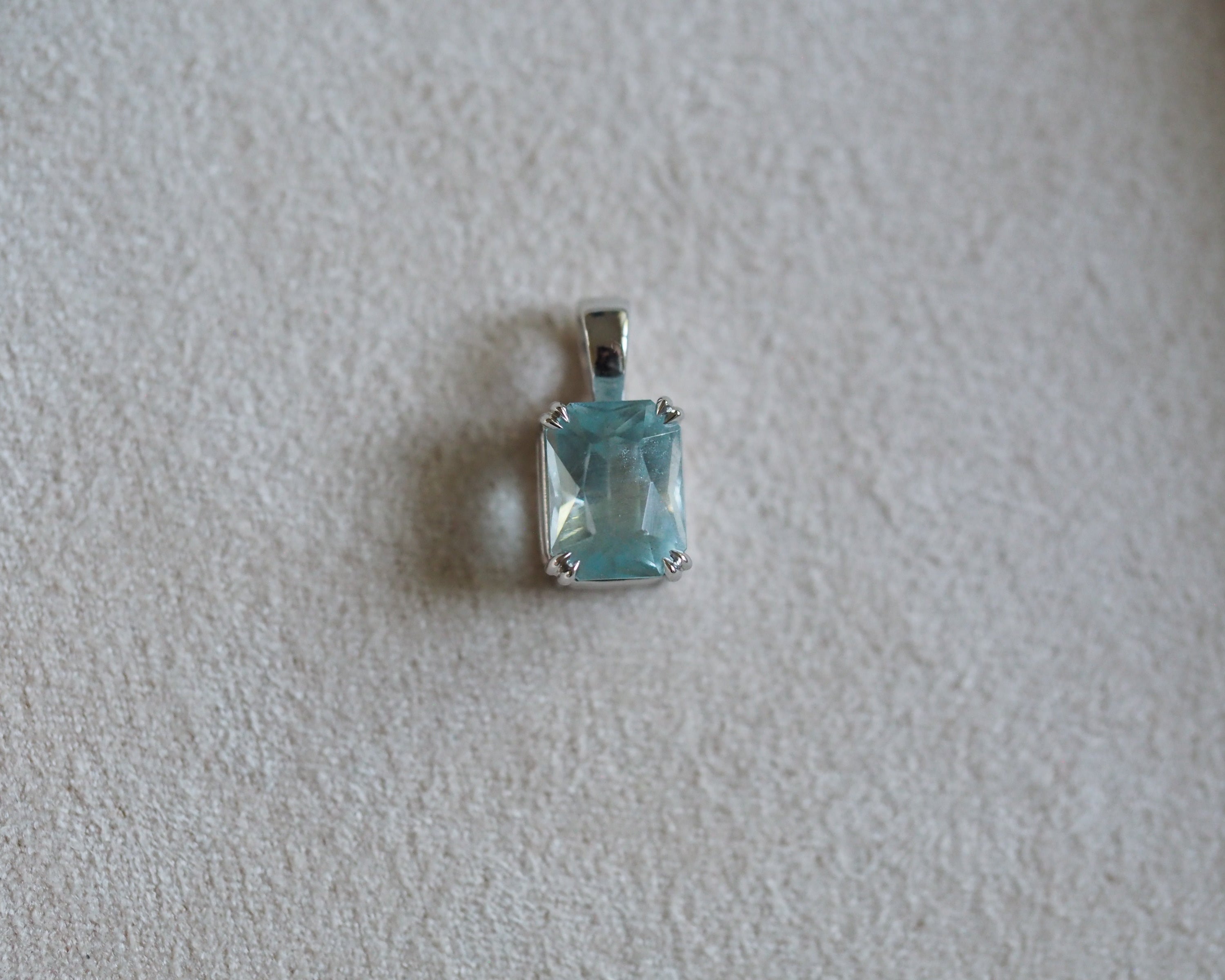Carolyn Radiant aquamarine pendant in front of a beige background