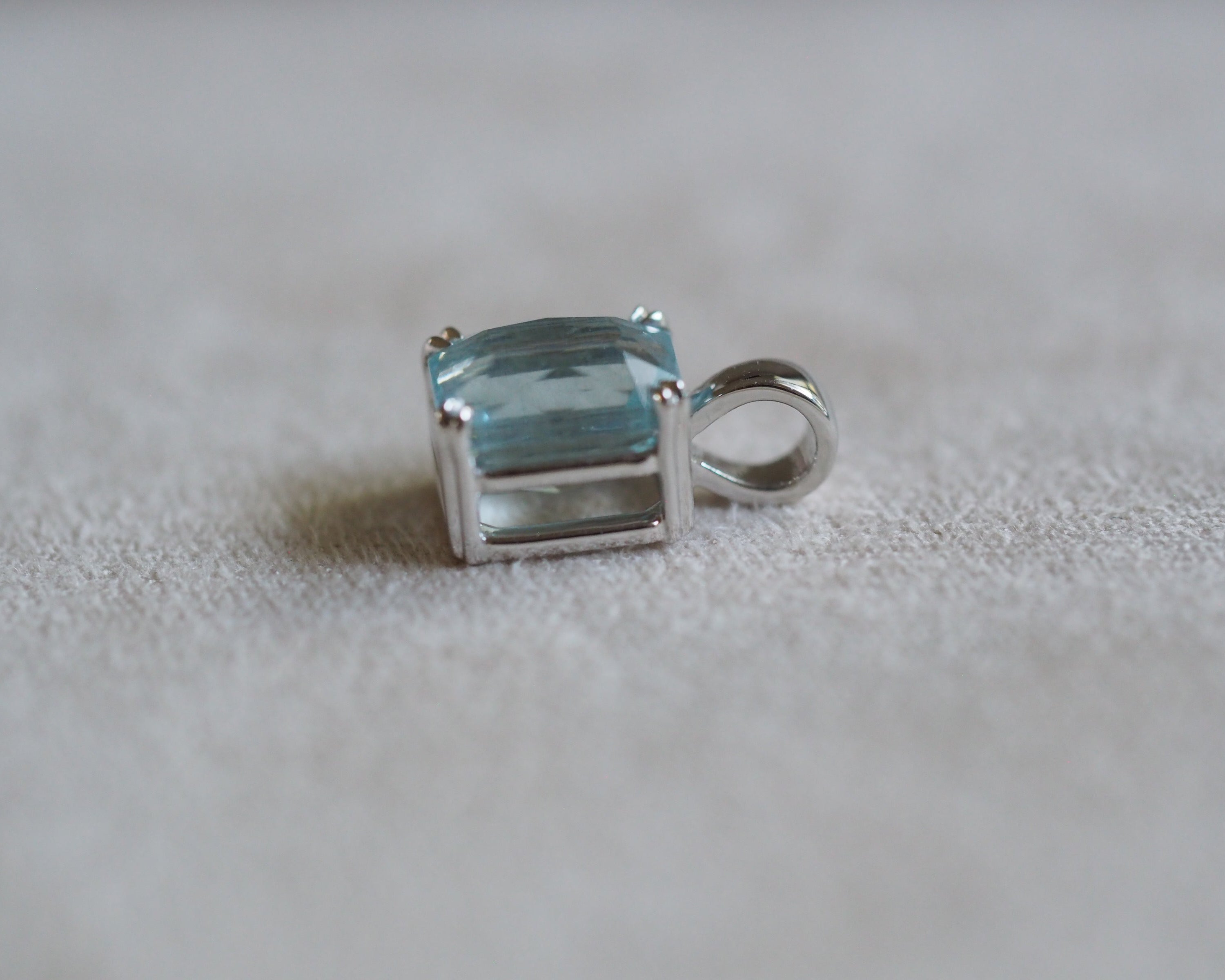 Carolyn Radiant aquamarine pendant in front of a beige background side