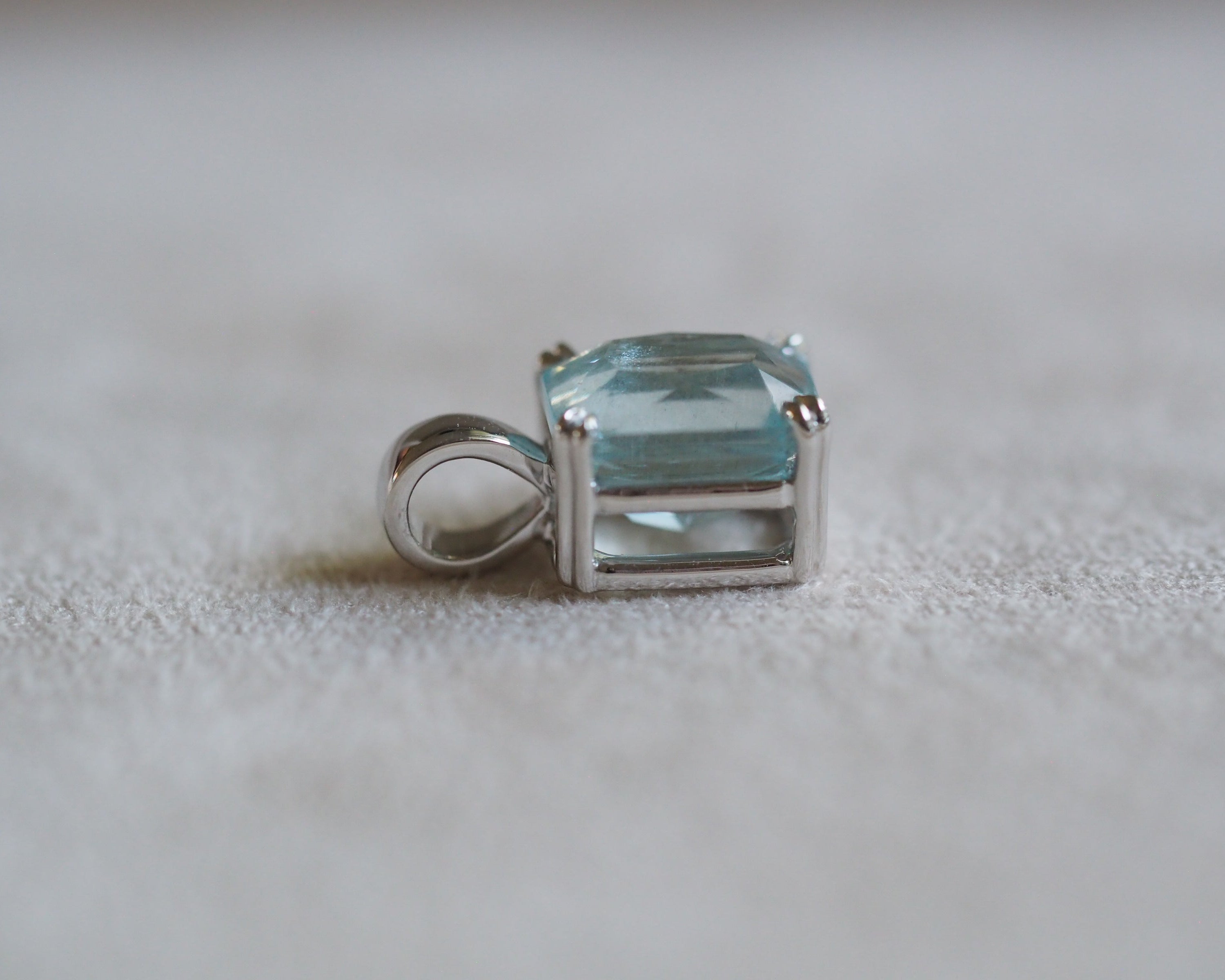 Carolyn Radiant aquamarine pendant in front of a beige background side