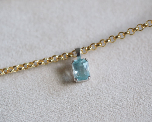Carolyn Radiant aquamarine pendant in front of a beige background with chain