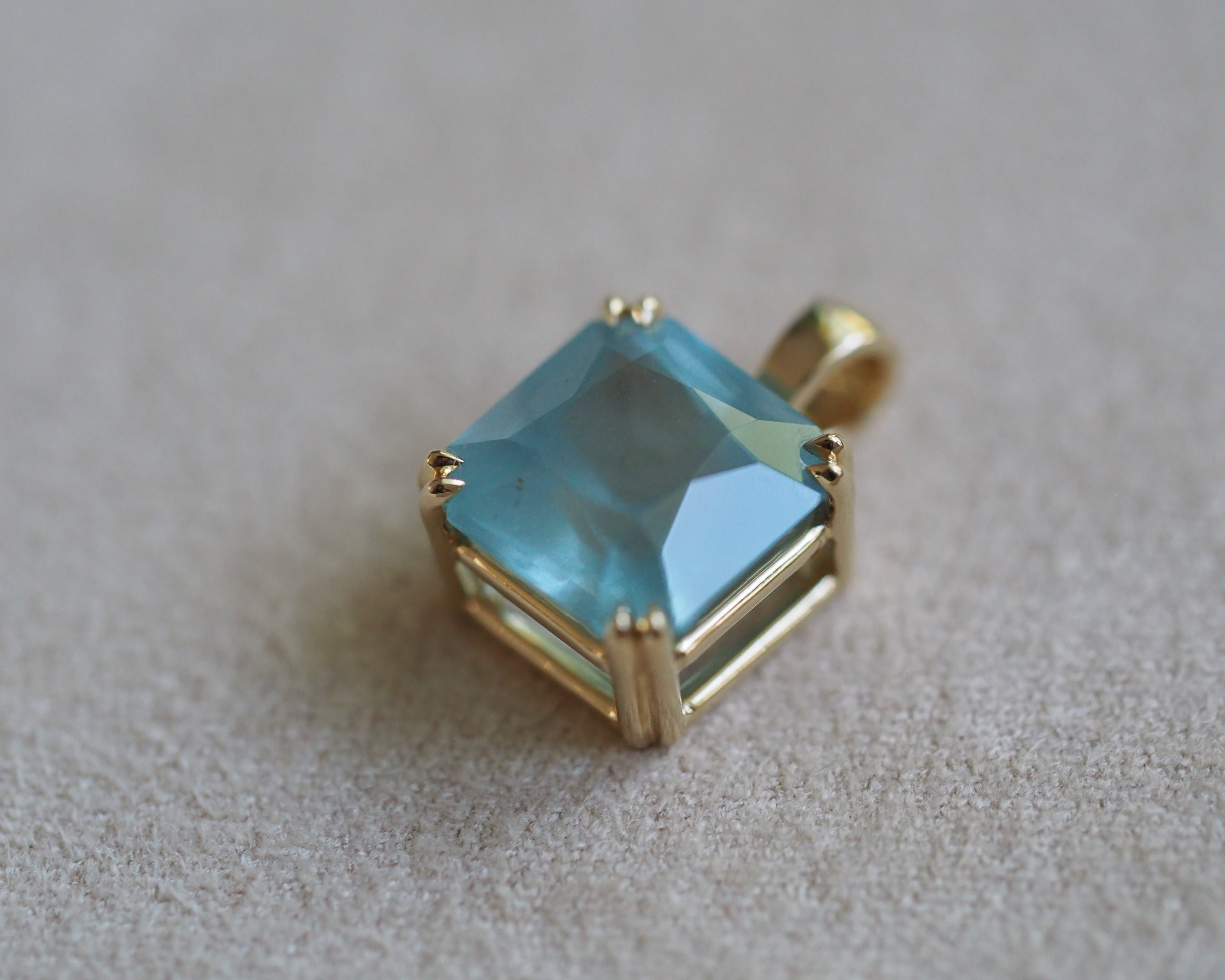Carolyn Asscher Aquamarine pendant in front of a beige background