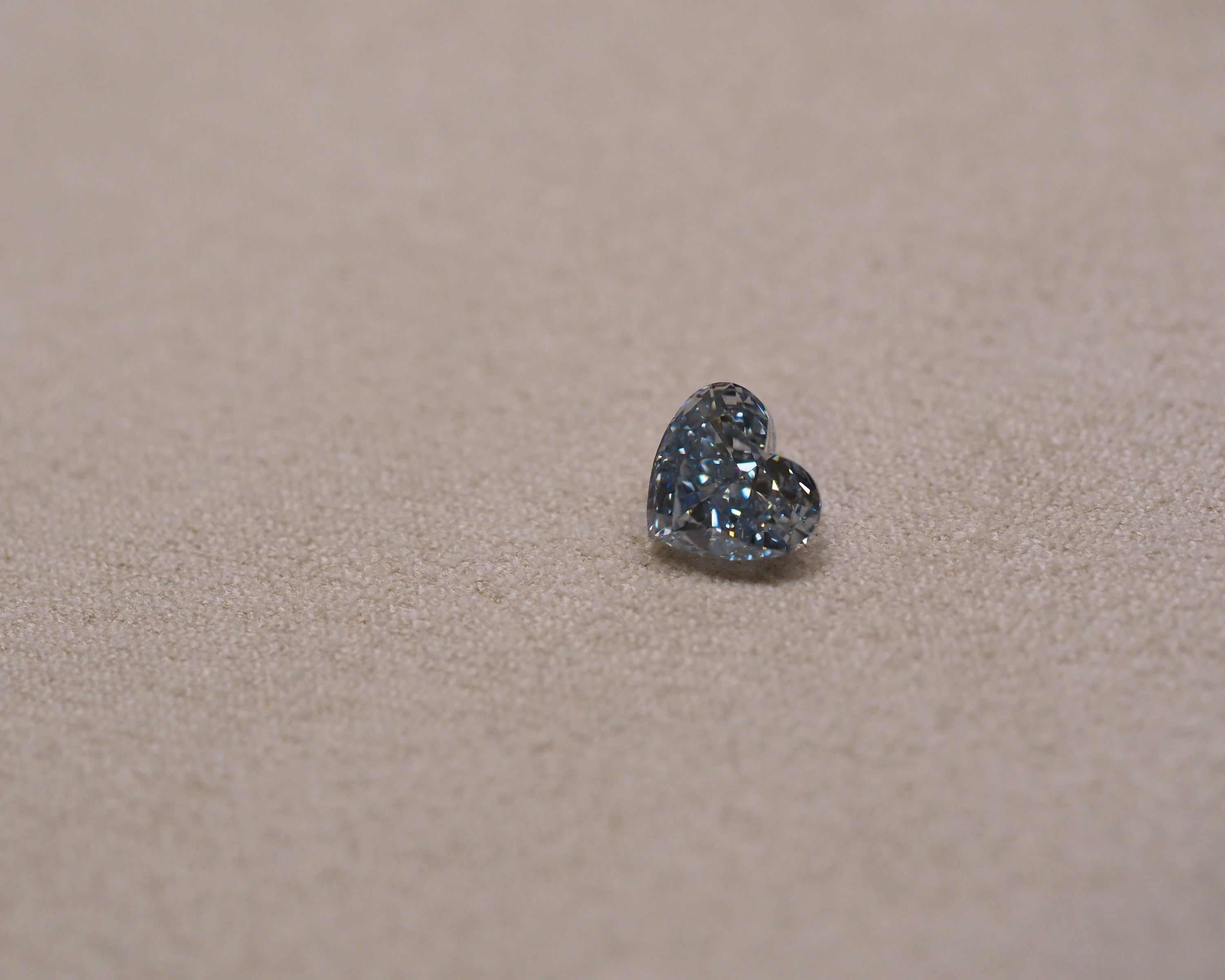 Heart shaped blue lab grown diamond on a beige background table