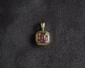 A square pendant featuring a cushion-cut pink gemstone in a gold bezel setting, displayed on a dark textured background.
