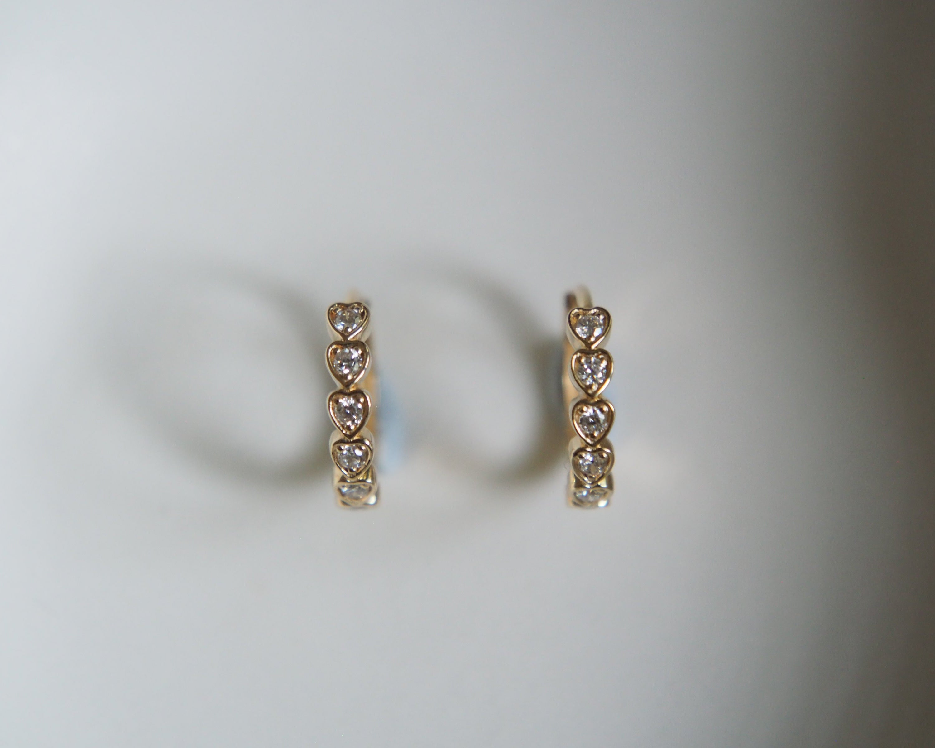 Pair of gold heart-shaped earrings on a light gray background